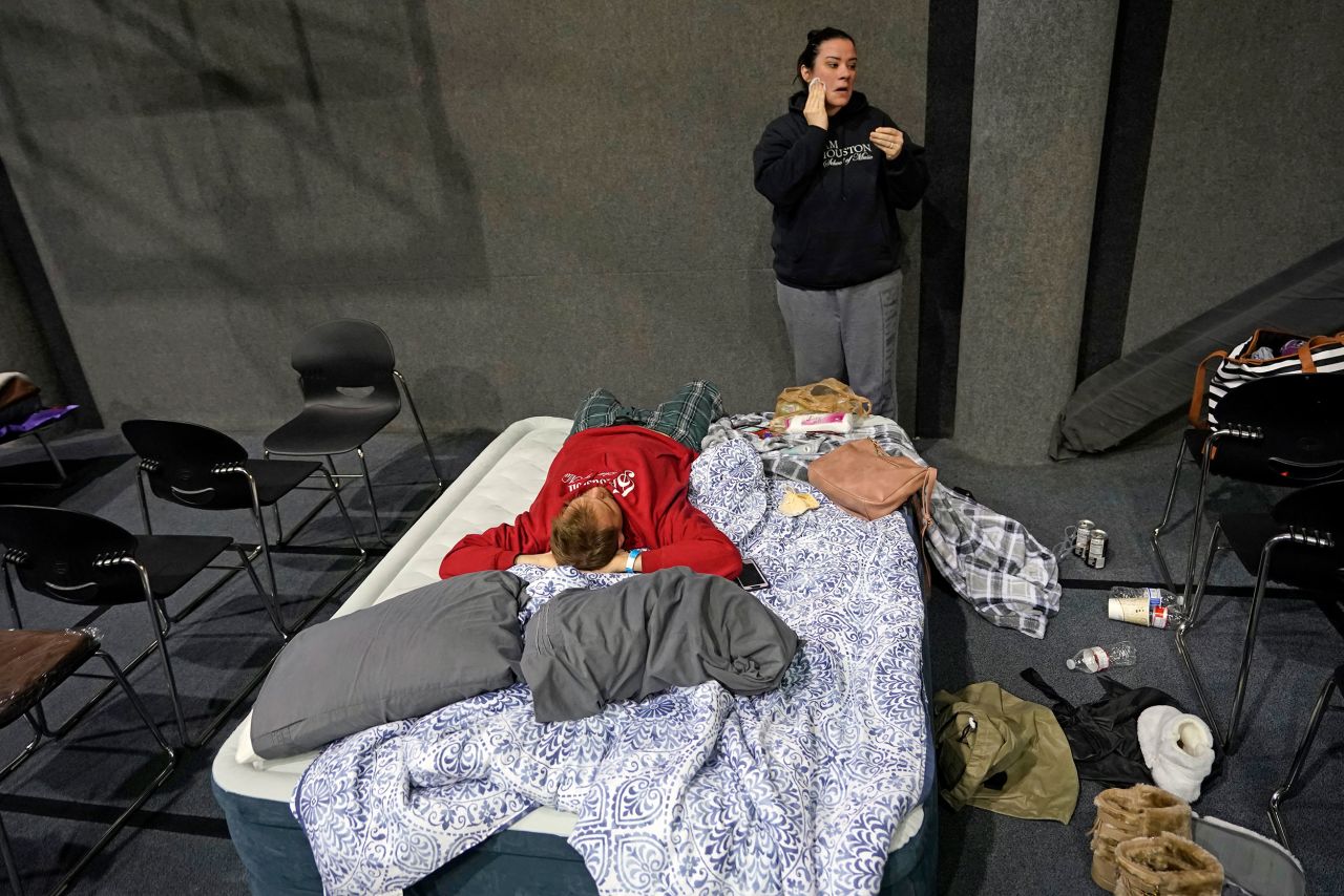 Bethany Fischer washes her face as her husband, Nic, lies on a mattress at a church in Houston on Tuesday. The couple lost power to their home.