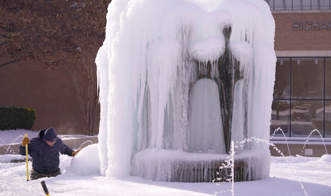 City of Richardson worker Kaleb Love works to clear ice from a water fountain Tuesday in Richardson, Texas.   