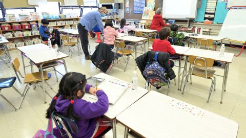 Binasa Musovic (left), an educational paraprofessional, and teacher Chris Frank (right), instruct blended learning students on the first day back to school, December 7, 2020, at Yung Wing School P.S. 124 in New York City. 