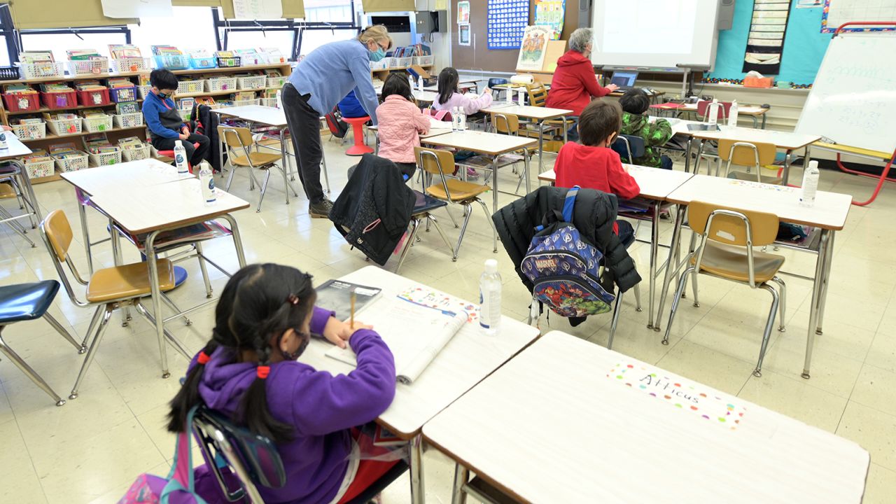 Binasa Musovic (left), an educational paraprofessional, and teacher Chris Frank (right), instruct blended learning students on the first day back to school, December 7, 2020, at Yung Wing School P.S. 124 in New York City. 
