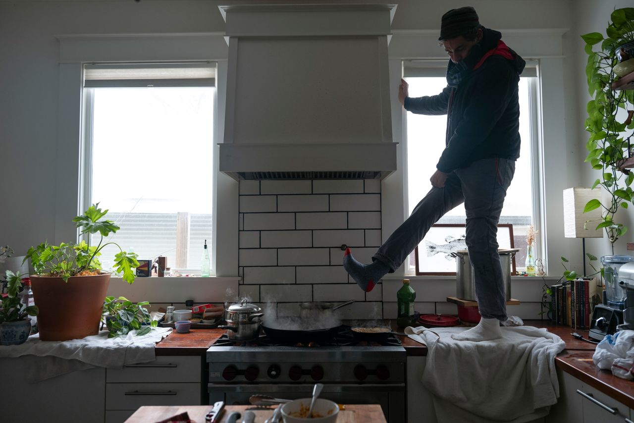 Jorge Sanhueza-Lyon stands on his kitchen counter to warm his feet over his gas stove in Austin.