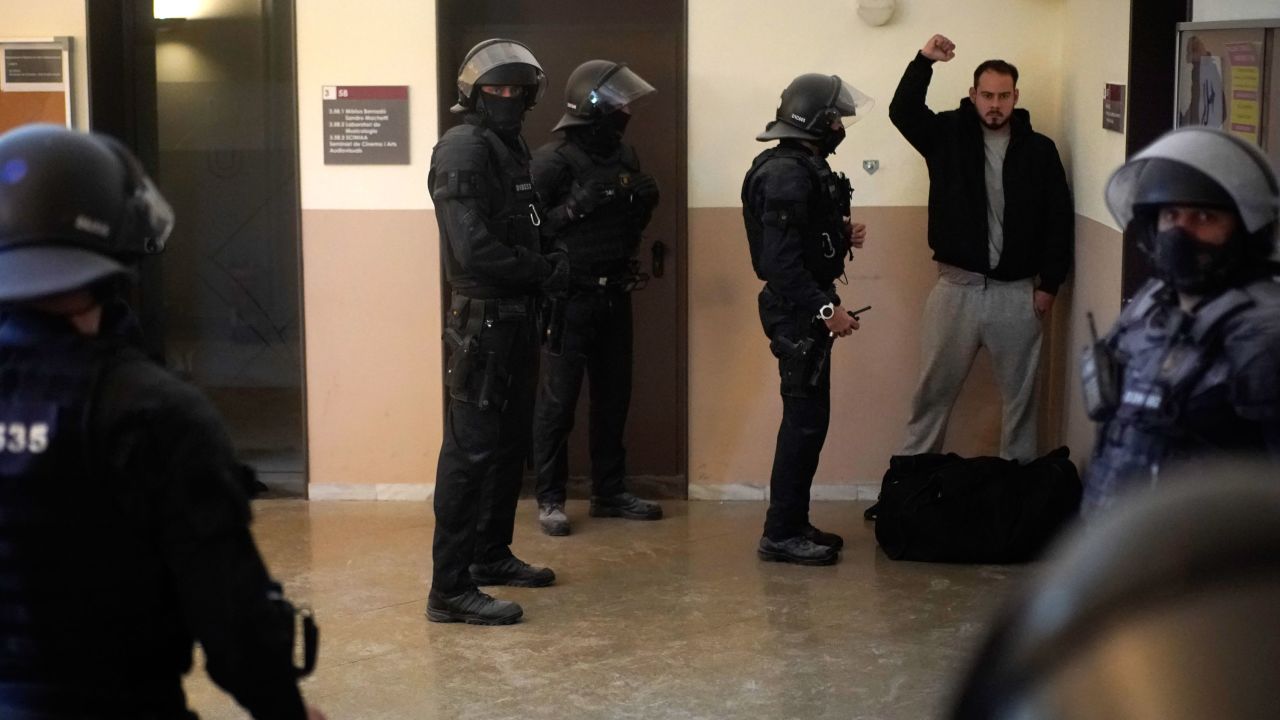The rapper reacts next to police officers before being detained on Tuesday.
