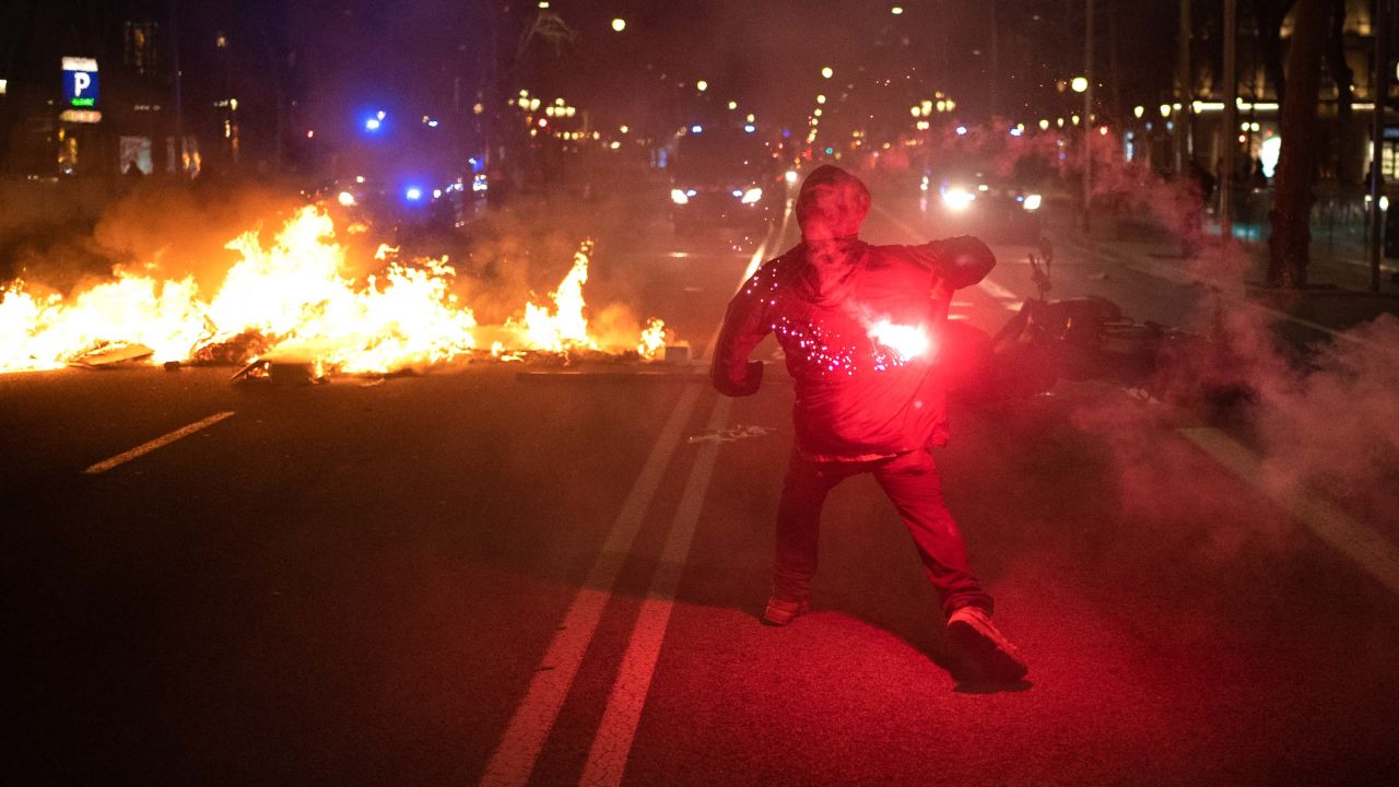 A demonstrator throws a flare at police during clashes after a protest condemning the arrest of rapper Pablo Hasel in Barcelona, Spain on Tuesday.