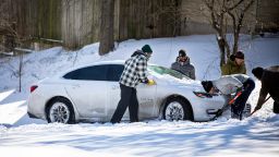A man shovels snow from under a car stuck on a hill on February 15, 2021 in East Austin, Texas. Winter storm Uri has brought historic cold weather to Texas, causing traffic delays and power outages.