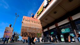 Supermarket workers hold placards in protest in front of a Food 4 Less supermarket in Food 4 Less, California on February 3, 2021, after a decision by owner Kroger to close two supermarkets rather than pay workers an additional $4.00 in "hazard pay" for their continued work during the coronavirus pandemic. - Kroger, which owns Ralphs and food 4 Less, said it will close one of each store in April after the Long Beach city council passed a law mandating "hazard pay" for grocery store workers. Long Beach was the first city in the region to approve a hazard pay ordinance. (Photo by Frederic J. Brown/AFP/Getty Images)