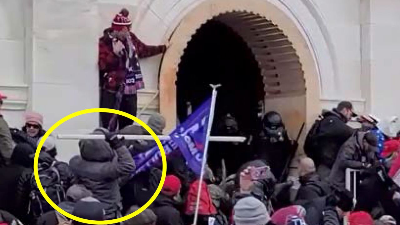 In this photo submitted in court filings by the Department of Justice, a rioter throws a sharpened pole at Capitol Police Officers.
