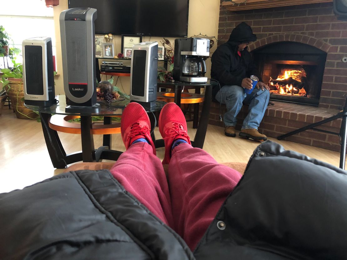 Eric Siner, Jr. warms his feet while his father sits by the fireplace after their neighbor hooked up their heaters to his generator. 
