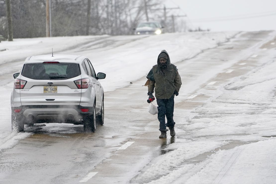 With many of the downtown sidewalks in Jackson, Mississippi covered with ice, a pedestrian walks on a street as cars pass him on Wednesday.