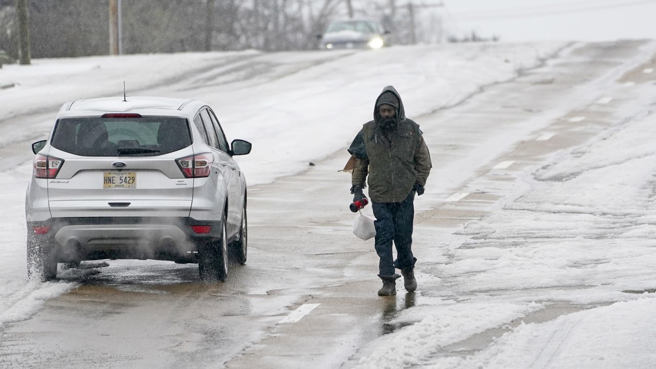 With many of the downtown sidewalks in Jackson, Mississippi covered with ice, a pedestrian walks on a street as cars pass him on Wednesday.