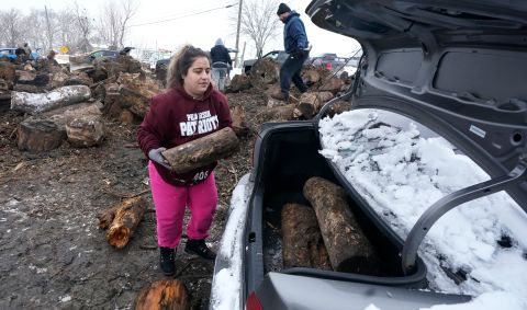 Sara Castillo loads firewood into her car in Dallas on Wednesday. Castillo's family lost their power on Sunday.
