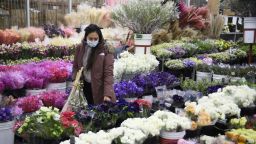 A customer wears a face mask while shopping for flowers displayed for sale from a wholesale merchant ahead of the Valentine's Day holiday at the Southern California Flower Market on February 12, 2021 in Los Angeles, California. - While some florists note an increased demand for socially distant gifts, the Covid-19 pandemic has impacted global supply chains and shut down most large events including weddings where flowers are popular. The Valentine's Day and Mother's Day holidays are historically the two busiest days of the year for floral businesses. (Photo by Patrick T. FALLON / AFP) (Photo by PATRICK T. FALLON/AFP via Getty Images)