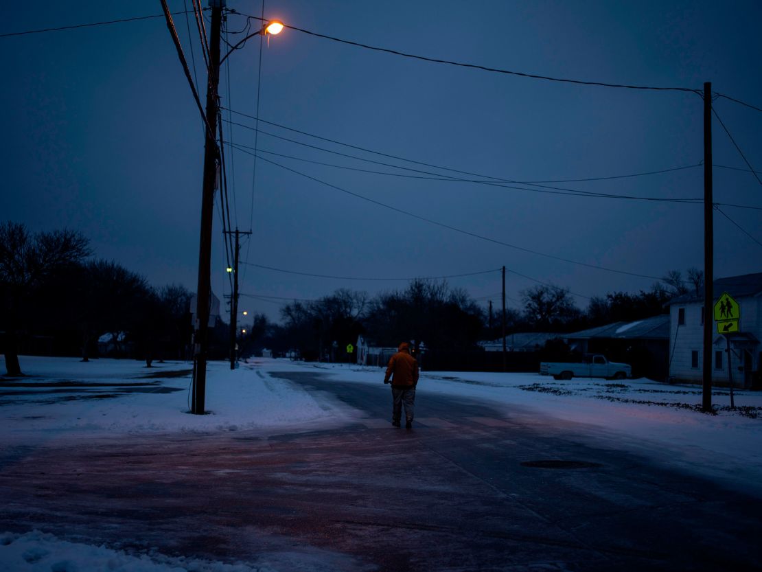 A man walks home through his neighborhood in Waco, Texas, as mass power outages left millions in the state stranded in the dark and cold. This deep freeze event was caused by an arctic air mass that drifted south, but its connection to climate change remains a topic of debate among scientists.