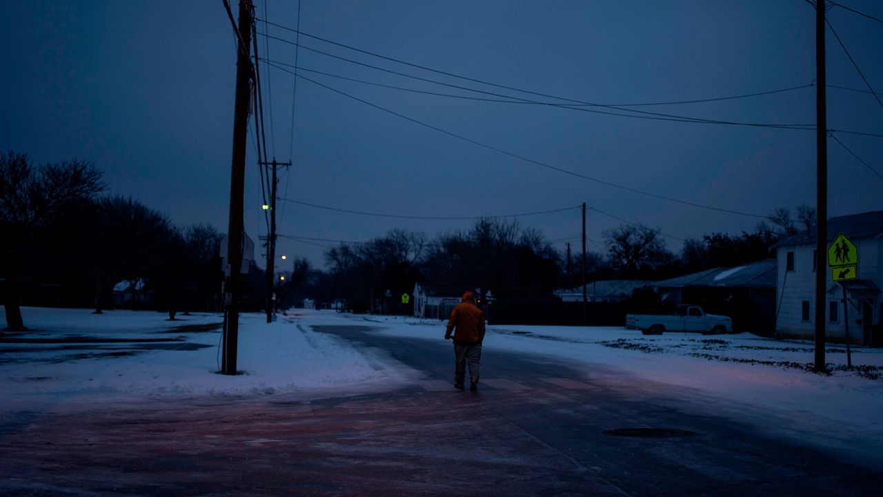 A man walks home through his neighborhood in Waco, Texas, as mass power outages left millions in the state stranded in the dark and cold. This deep freeze event was caused by an arctic air mass that drifted south, but its connection to climate change remains a topic of debate among scientists.