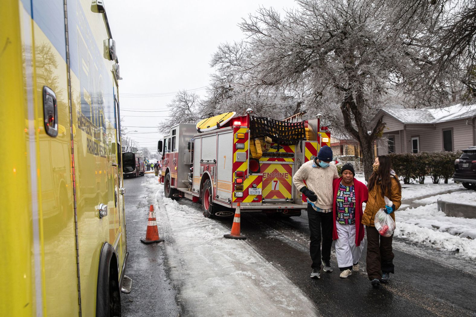 Nathan Halaney and Katherine Pena help their neighbor, Brenda Davis, from the scene of a nearby structure fire in Austin, Texas, on Wednesday.