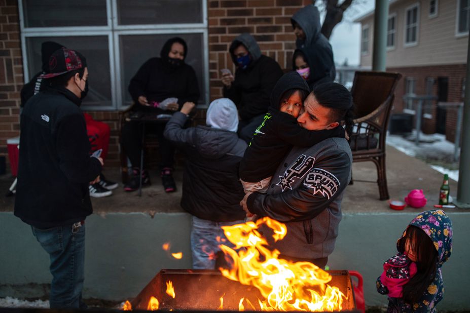 Eric Traugott warms up his young son, Eric Jr., beside a fire made from a discarded wooden armoire outside of their apartment in Austin on Wednesday.