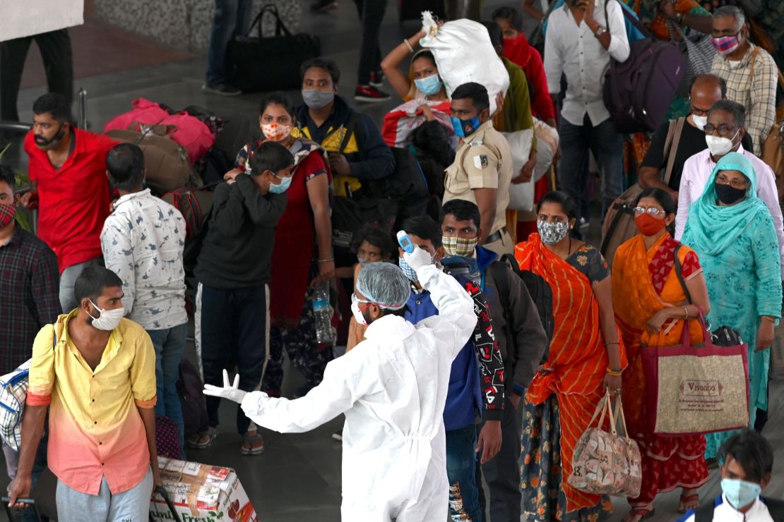 A health worker checks the body temperature of arriving passengers at a railway terminus in Mumbai on January 6, 2021.