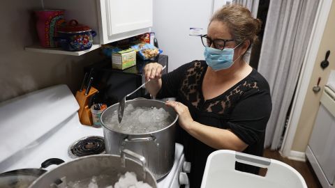 Marie Maybou melts snow on her kitchen stove in Austin on Friday. She is using the water to flush her home's toilets after the city water stopped running.