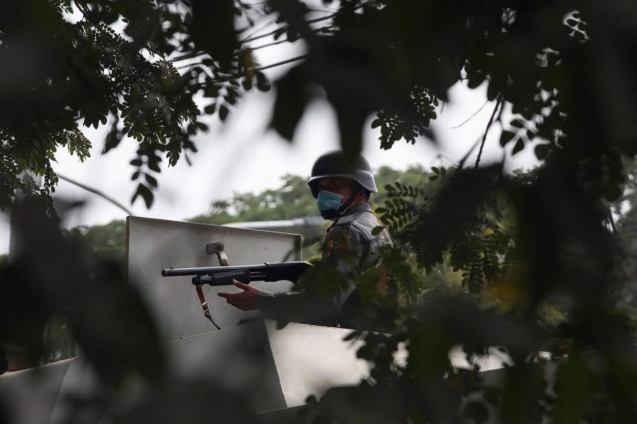 A police officer aims a gun toward protesters during a demonstration in Mandalay on February 20.