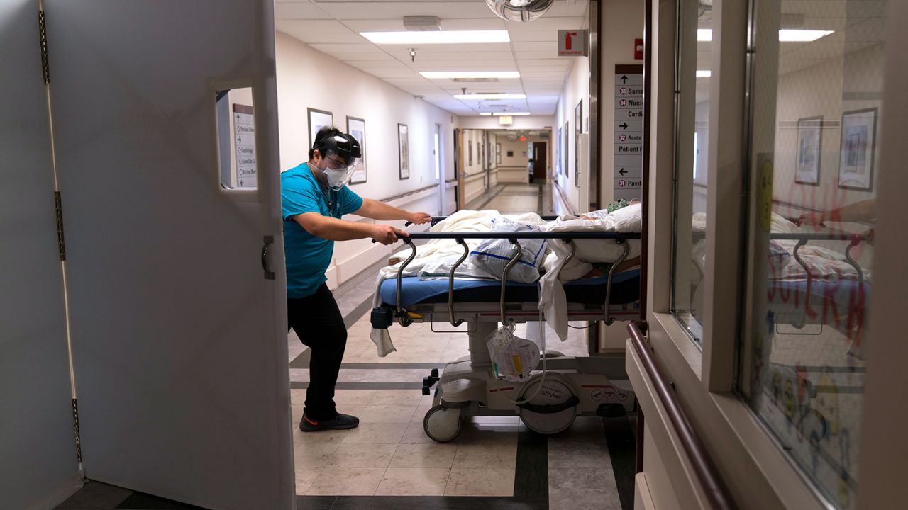 Medical transporter Adrian Parrilla transports a patient into a COVID-19 unit at Mission Hospital in Mission Viejo, Calif., Friday, Feb. 19, 2021. California's virus cases, infection rates, and hospitalizations have dropped precipitously after reaching record highs in early January. (AP Photo/Jae C. Hong)