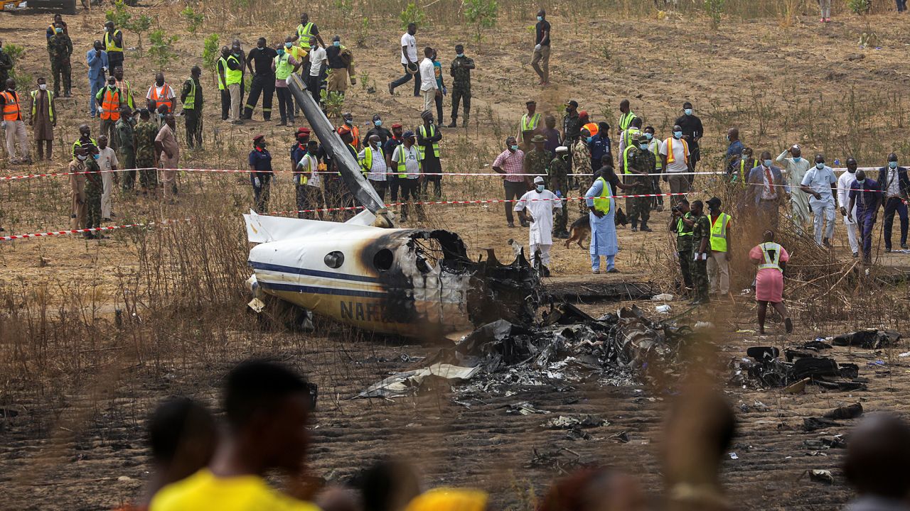 People and rescuers gather at the site where a Nigerian air force plane crashed while approaching the Abuja airport runway on Sunday