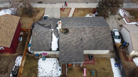 In this aerial view from a drone, people walk past a home with a hole in the roof from falling debris from an airplane engine on February 20 in Broomfield, Colorado. 