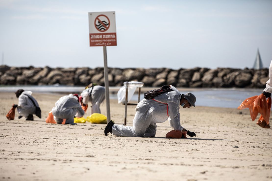 Volunteers wearing protective clothing search for tar along Israel's coast  in Herzilya Pituah, north of Tel Aviv on February 21.
