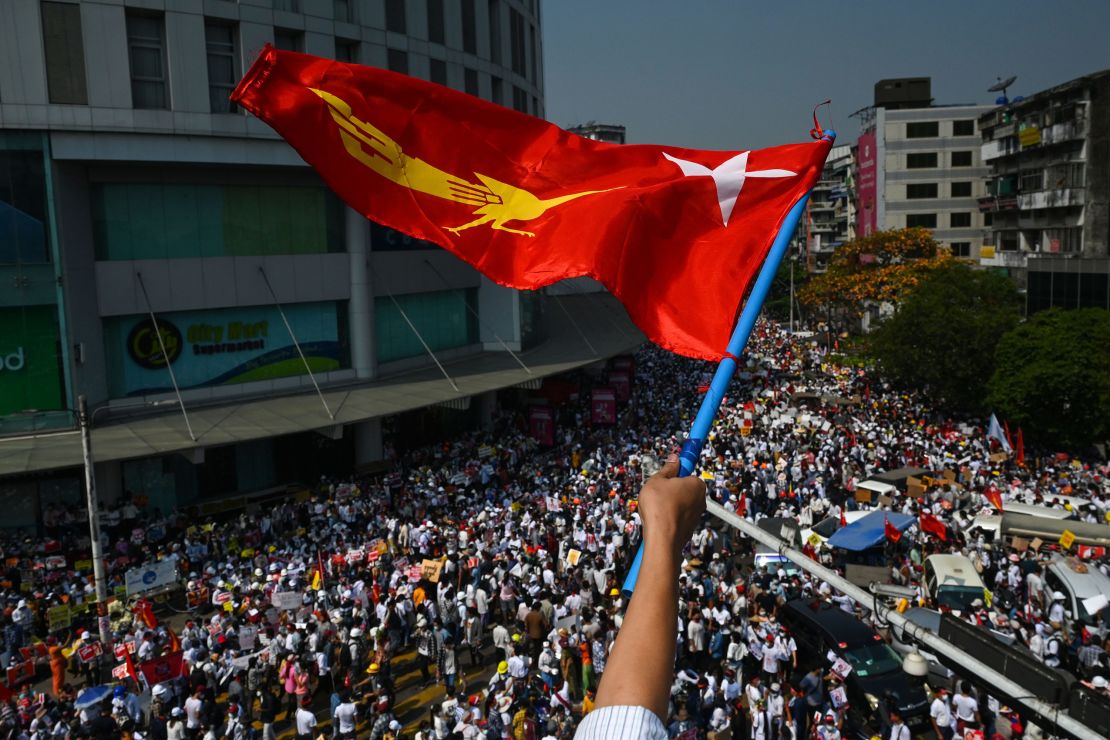 A protester waves the National League for Democracy (NLD) flag while others take part in a demonstration against the military coup in Yangon on February 22.