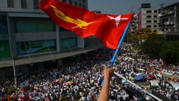 A protester waves the National League for Democracy (NLD) flag while others take part in a demonstration against the military coup in Yangon on February 22, 2021. 