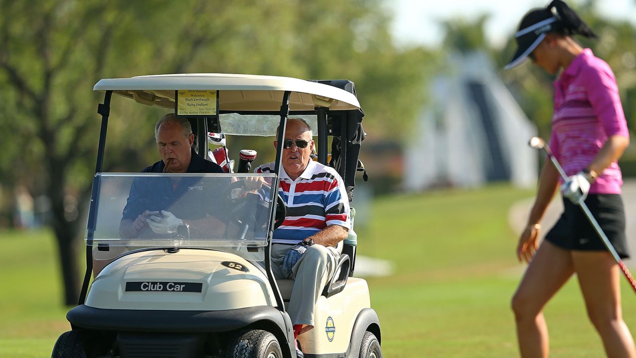 Former New York City Mayor Rudy Guliani and Rush Limbaugh look on as Michelle Wie plays during the Els for Autism Pro-am at The PGA National Golf Club on March 10, 2014 in Palm Beach, Florida.