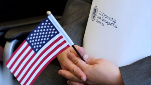 In this April 10, 2019, file photo, an applicant holds an American flag and a packet while waiting to take the oath to become a US citizen at a naturalization ceremony in Salt Lake City. 