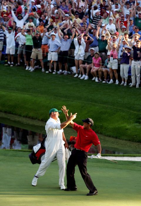 Woods celebrates with his caddie, Steve Williams, after his famous chip-in at the 2005 Masters. Woods went on to win his fourth green jacket.