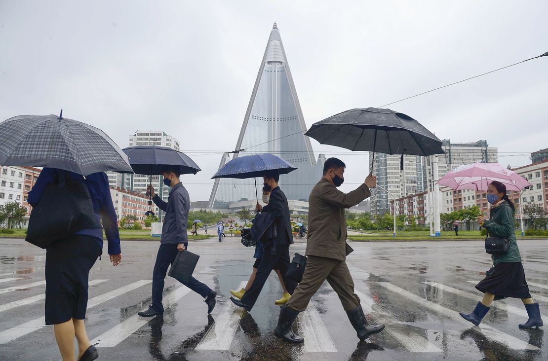People walk in the rain in Pyongyang on May 15, 2020, wearing face masks amid the coronavirus pandemic.