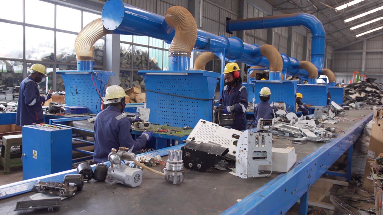 Workers sort e-waste using a system of conveyor belts across Enviroserve's recycling facility near Kigali.