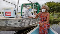 TOPSHOT - Olga D'arc Pimentel, 72, is vaccinated by a health worker with a dose of Oxford-AstraZeneca COVID-19 vaccine in the Nossa Senhora Livramento community on the banks of the Rio Negro near Manaus, Amazonas state, Brazil on February 9, 2021. (Photo by MICHAEL DANTAS / AFP) (Photo by MICHAEL DANTAS/AFP via Getty Images)
