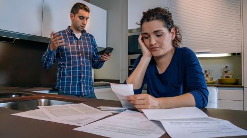 underscored couple in debt looking at bills and calculator
