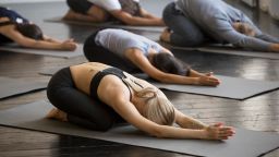 Group of young sporty people practicing yoga lesson with instructor, stretching in Child exercise, Balasana pose, working out, indoor close up, students training in club, studio