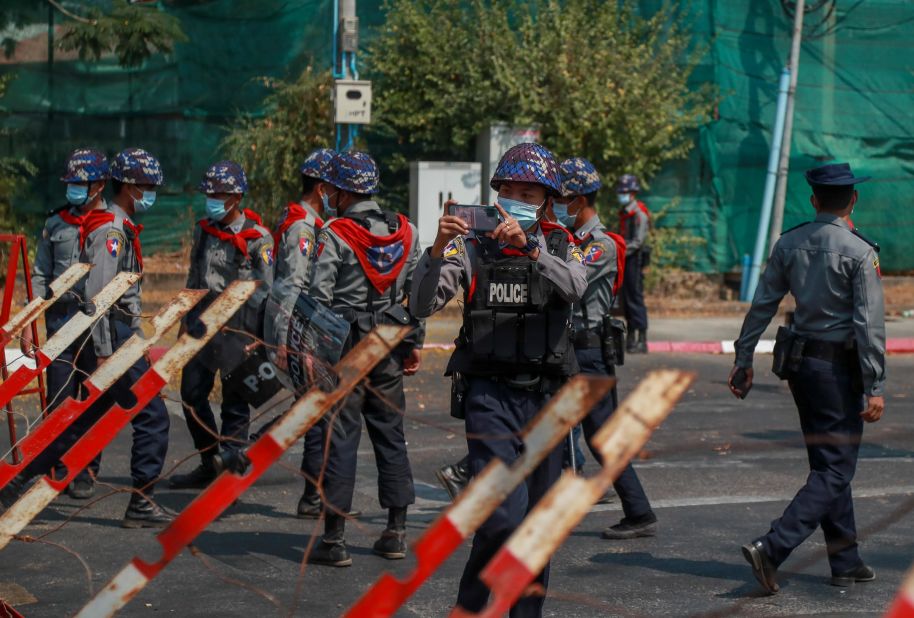 A police officer films protesters near the Indonesian Embassy in Yangon on February 24.