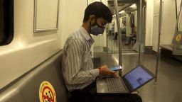 A man is seen on his laptop and phone while wearing a facemask and observing social distance on the Delhi Metro on its first day of reopening after 5 months of lockdown due to Covid-19. On the first day, the yellow line between HUDA City Centre and Samaypur Badli, will run from 7 to 11 am, and 4 to 8 pm in the 2nd phase. The metro will resume full services from September 12. (Photo by Naveen Sharma/SOPA Images/Sipa USA/AP)