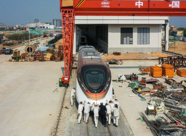 Workers move a section of an electric train in Guangzhou, China, on Saturday, February 20.