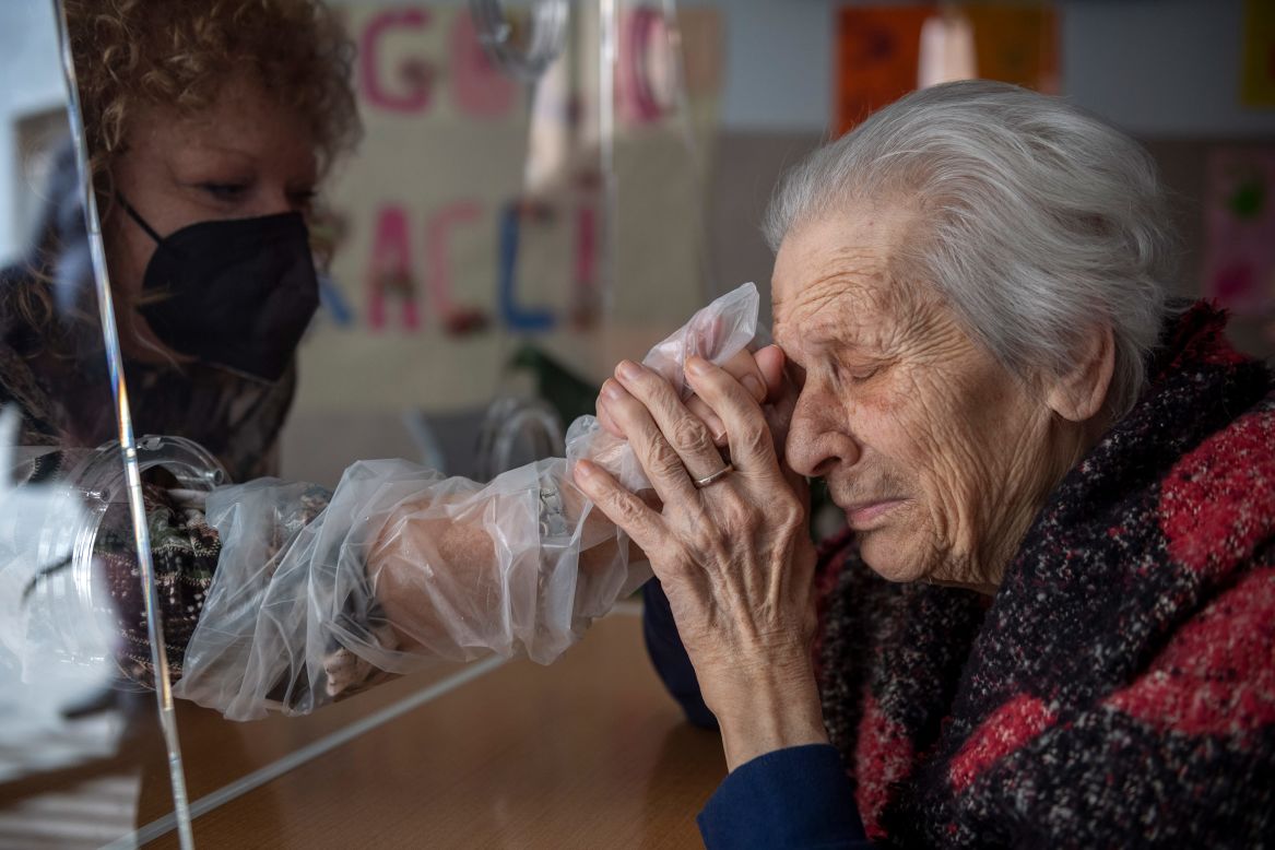 Anna, a resident of the Villa Sacra Famiglia Nursing Home, holds her daughter's hand in the Rome facility's "hug room" on Wednesday, February 24. The room allows residents and their families to touch one another while staying safe from Covid-19.