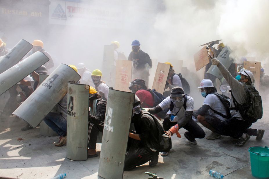 Protesters take cover as they clash with police in Yangon on February 28.