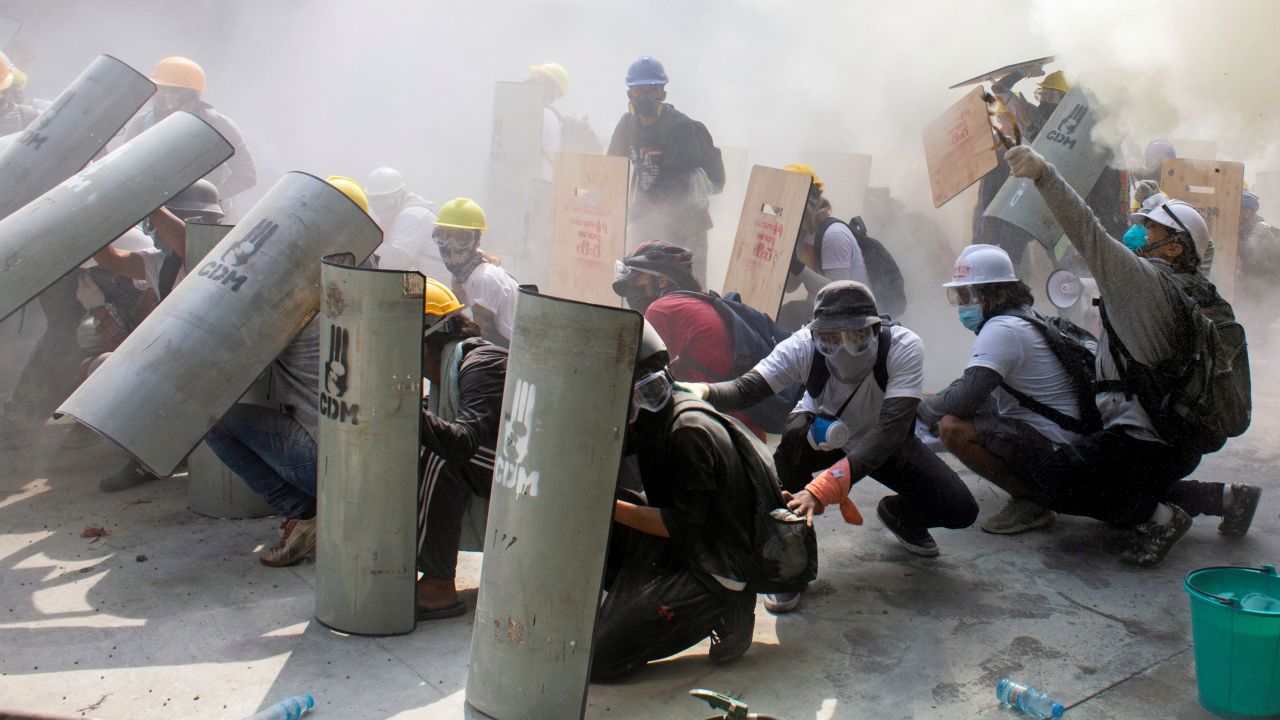 Protesters take cover as they clash with riot police officers during a protest against the military coup in Yangon, Myanmar, February 28.