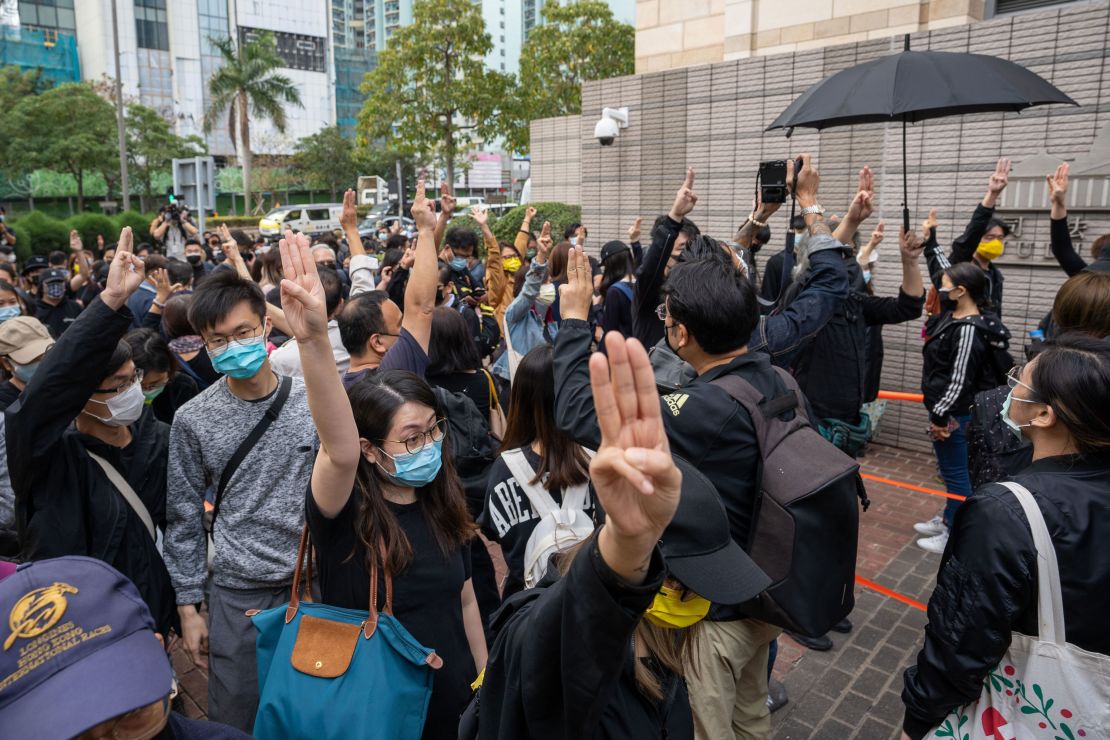 Pro-democracy activists gesture as they line up outside the West Kowloon court in support of the arrested activists.