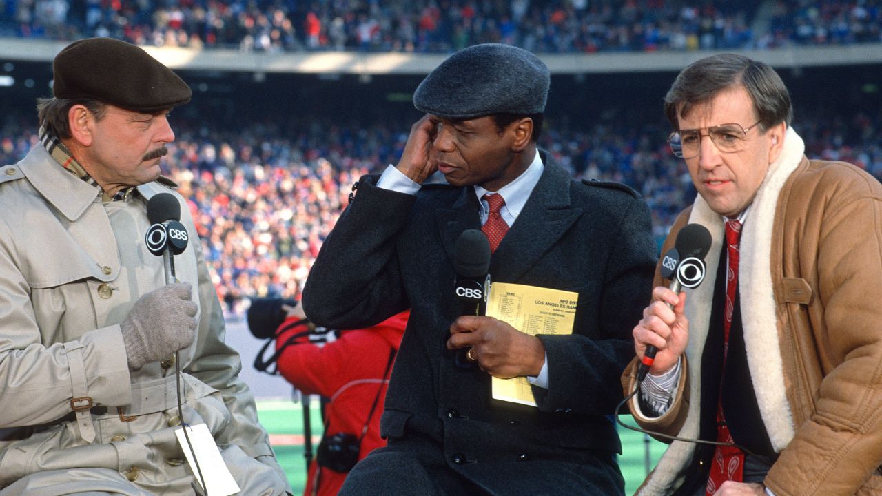 Irv Cross, center, talks with broadcast partners Dick Butkus, left, and Brent Musburger on the air prior to the start of an NFL game around 1989. 