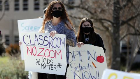 Demonstrators hold posters during a protest to reopen schools in Calabasas, California on March 1, 2021