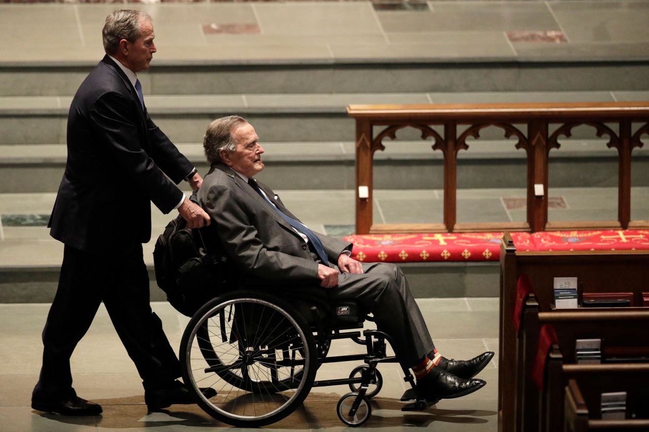 Bush pushes his father's wheelchair at the funeral service for his mother, Barbara, in April 2018.