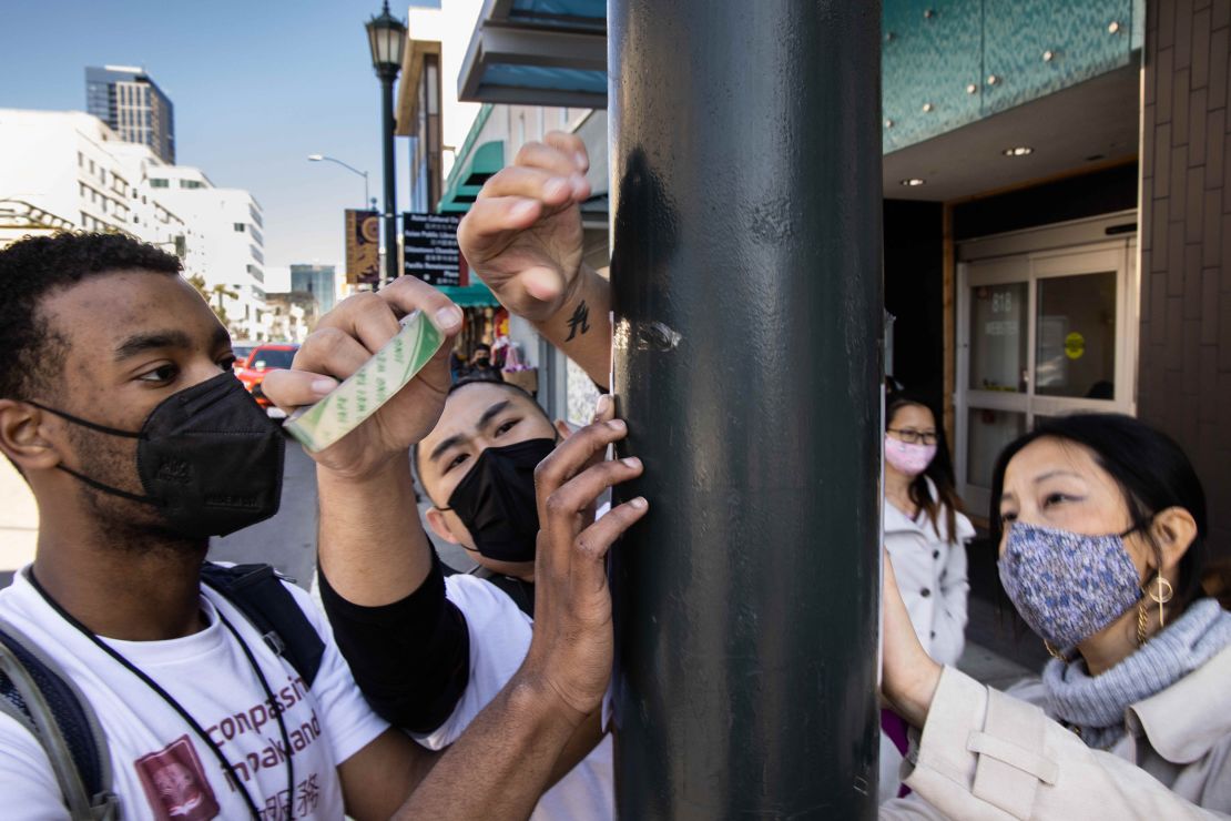 Community members tape notices in Oakland's Chinatown to help the neighborhood keep safe against crime on February 27, 2021.