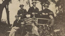 Photograph shows a group of men and two women gathered around the railing of a boat pulled ashore. Two of the men wear uniforms, and the others may possibly be teachers who came to the Beaufort area in 1862.