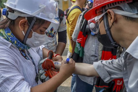 An anti-coup protester writes vital emergency information of another protester on his arm in Yangon.