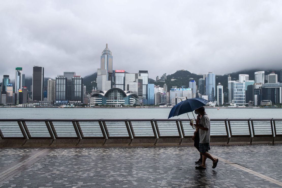 Two pedestrians using umbrellas on Kowloon's Tsim Sha Tsui waterfront after Typhoon Higos swept Hong Kong overnight on Aug. 19, 2020.